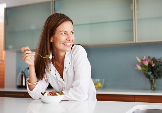 smiling Women in kitchen eating salad at counter