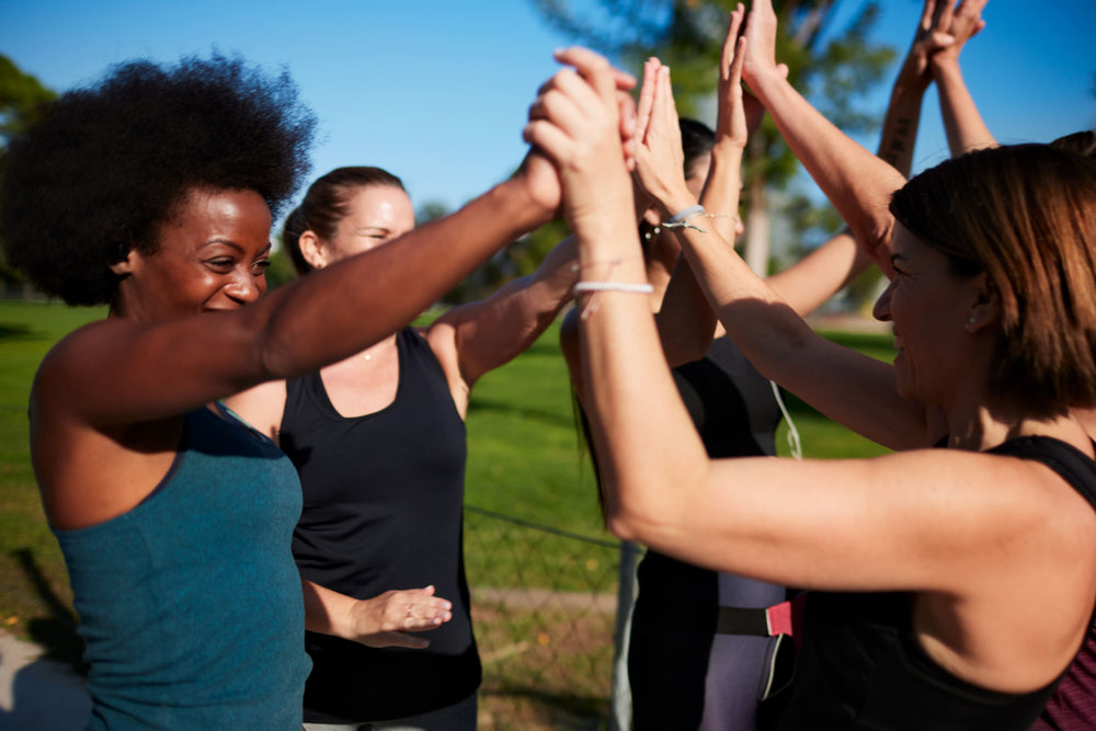 women in a park happy and high fiving