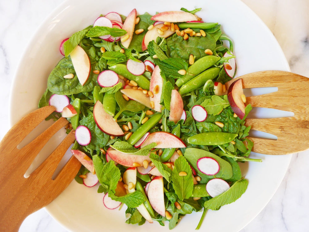 Summer salad in a bowl on a counter with two wooden forms