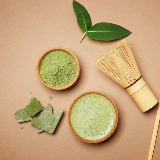 Matcha green tea powder in a bowl with a whisk and leaves on a beige background Matcha green tea powder in a bowl with a whisk and leaves on a beige background