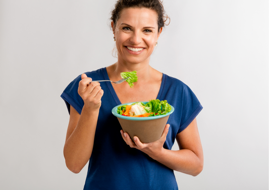 woman eating salad with grey background