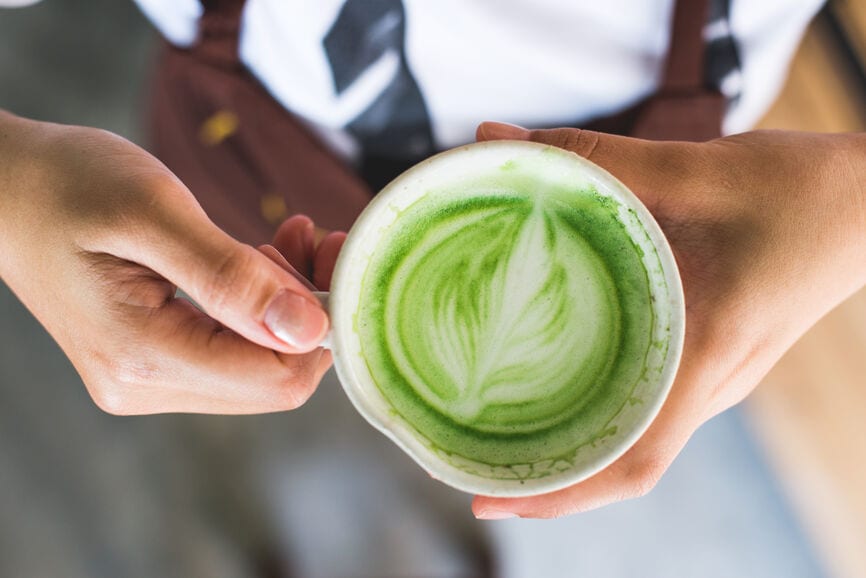 Person holding mug with matcha in it. 