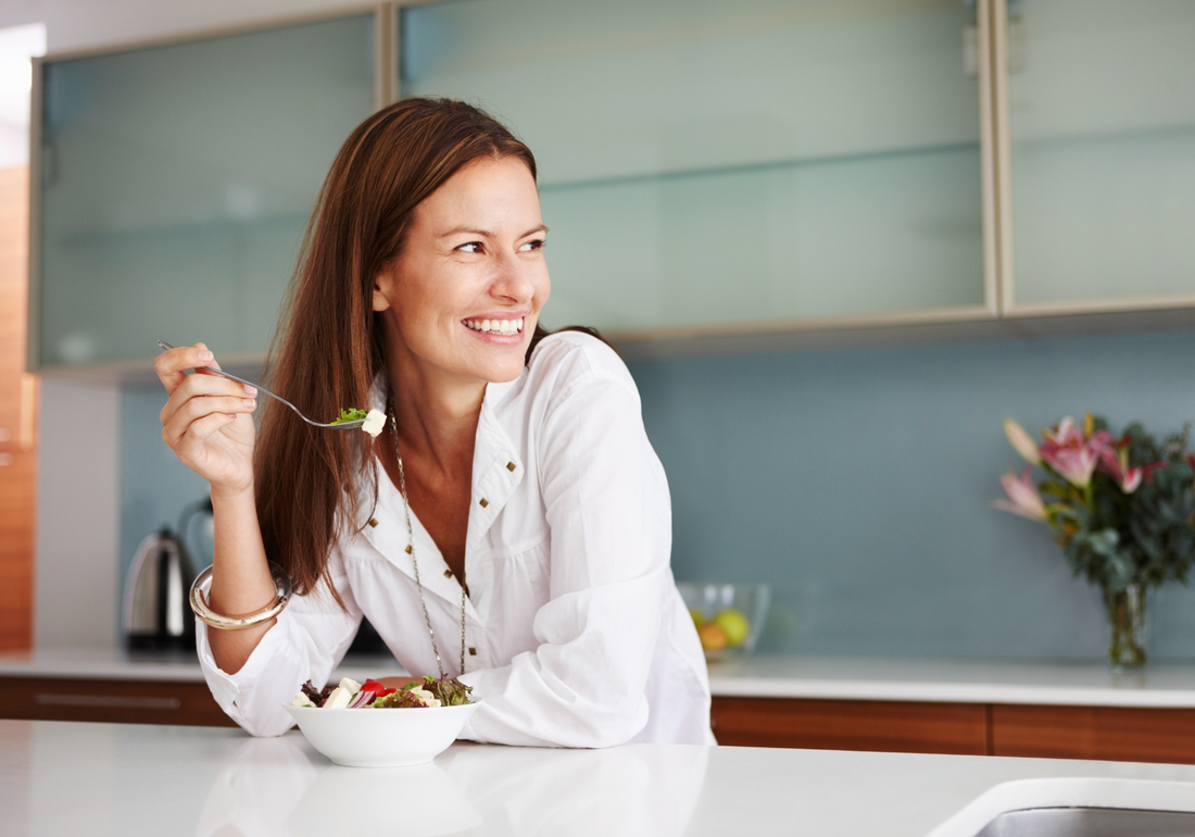 smiling Women in kitchen eating salad at counter