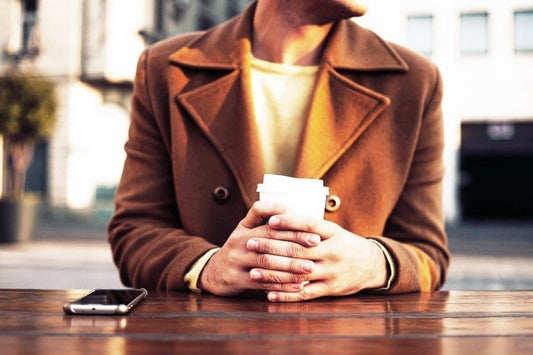 Clean Coffee Alternatives person in brown jacket with coffee at a table outside