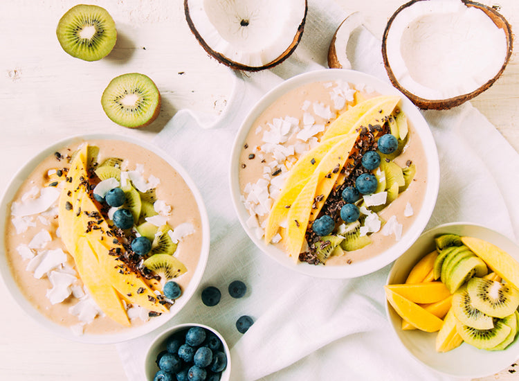 smoothie bowls with fruit in them on a white table cloth