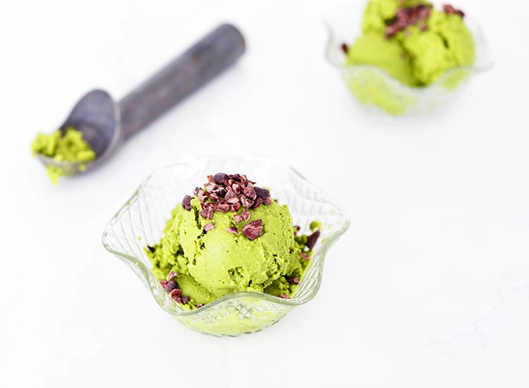 Matcha icecream in a glass next to an icecream scoop