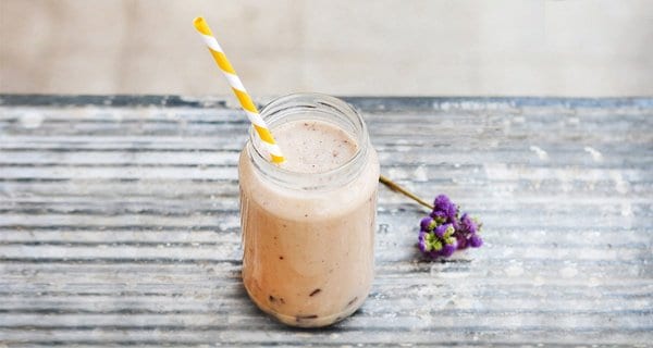 Superblend shake in a glass jar with a yellow striped straw.