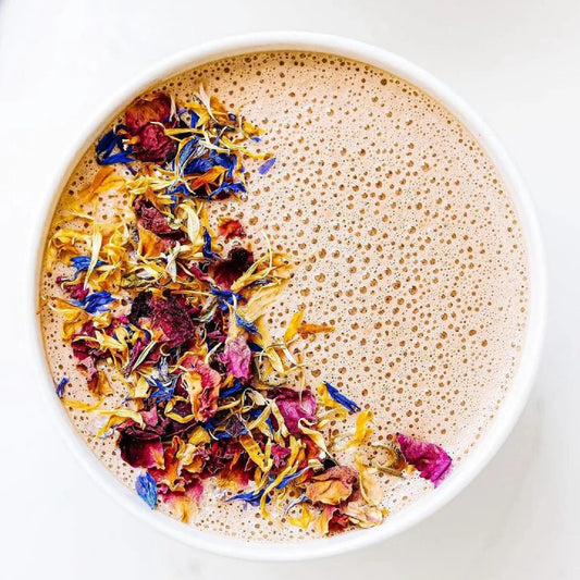 Foamy beverage with colorful dried flowers in a white bowl on a light background