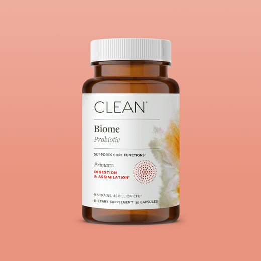 Brown supplement bottle labeled 'CLEAN Biome Probiotic' on a peach background