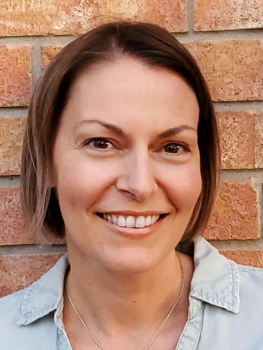 Woman smiling in front of a brick wall