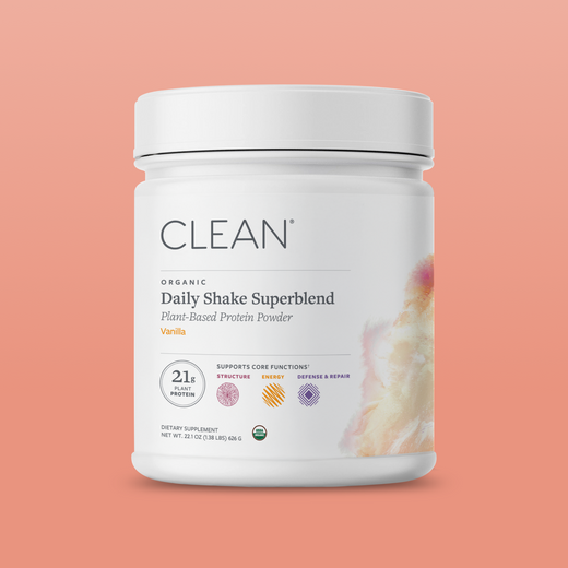 Container of Clean Daily Shake Superblend protein powder on a peach background
