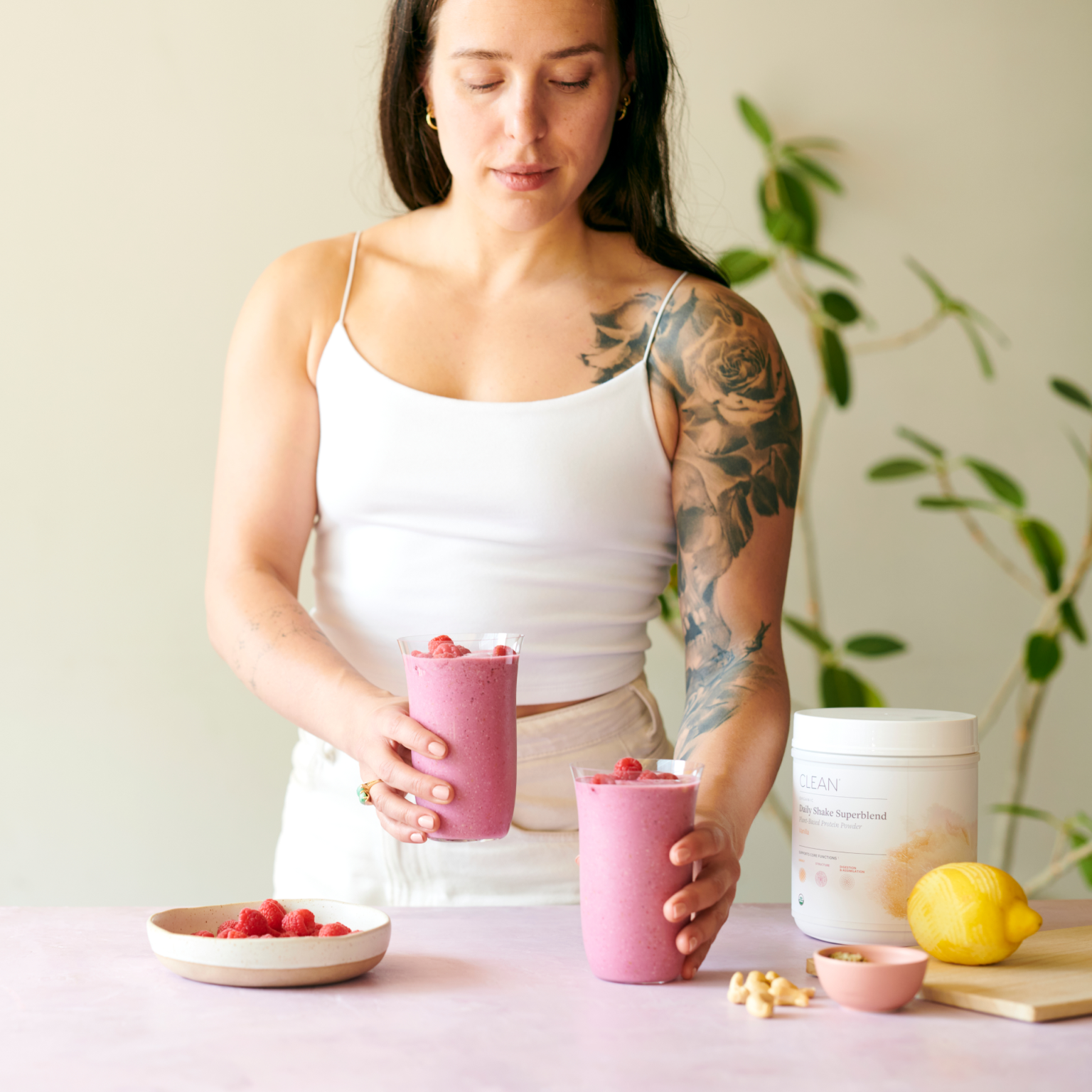 Jump to Woman holding pink smoothies with ingredients on a table in product gallery