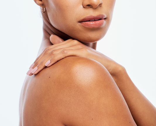 Close-up of a woman's shoulder and neck with her hand resting on her upper arm, showing smooth skin against a plain white background.