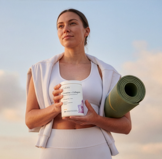 Woman holding a supplement container and yoga mat against a sky background