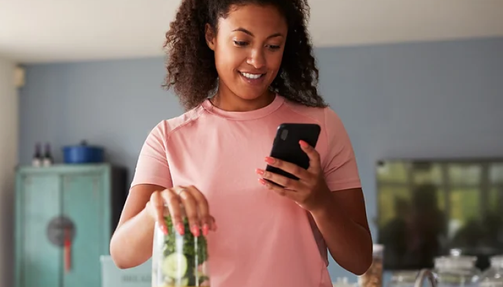 Woman preparing a salad and checking her cell phone