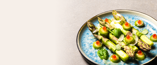 Plated dish of asparagus with garnishes on a light background