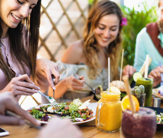 group of friends happily eating healthy food at a table outside